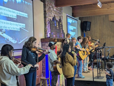 A group of teenage musicians on a stage playing instruments and singing praise songs.
