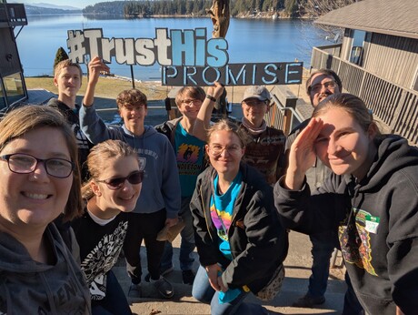A group of Pathfinders pose for a picture in front of Hayden lake during the 2025 #TrustHisPromise Pathfinder Teen Retreat.