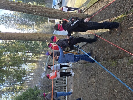 Blindfolded teens navigate a ropes course aided by verbal commands from their peers