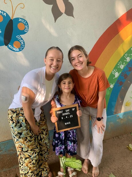 Students stand by kid at mission sschool